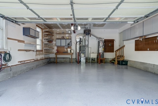 Garage with an epoxy floor finish, built-in shelving, mounted cabinetry, and a utility sink