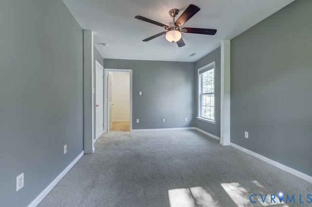 Neutral-toned walls, ceiling fan with integrated lighting, carpeted flooring, and a double-hung window