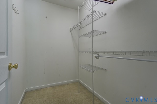Walk-in closet with wire shelving system and hanging rods, featuring a brass-toned doorknob