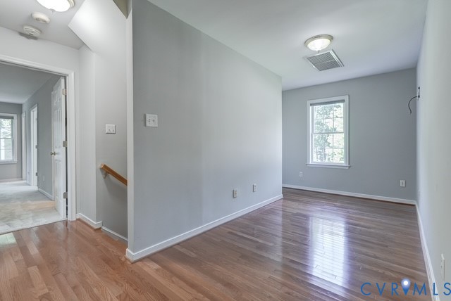 Hardwood flooring, light gray wall tones, natural light from a window, and white trim