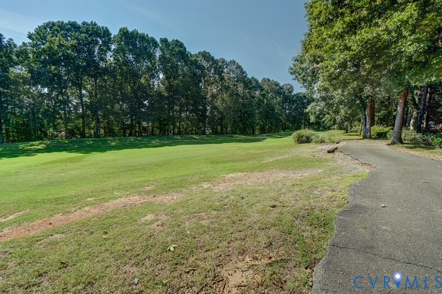 Expansive green space bordered by mature trees and a paved pathway