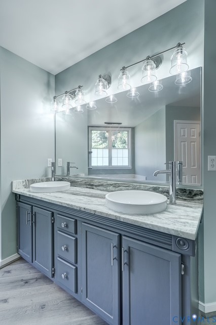 Double vanity with gray cabinetry, vessel sinks, chrome fixtures, and a large wall-mounted mirror