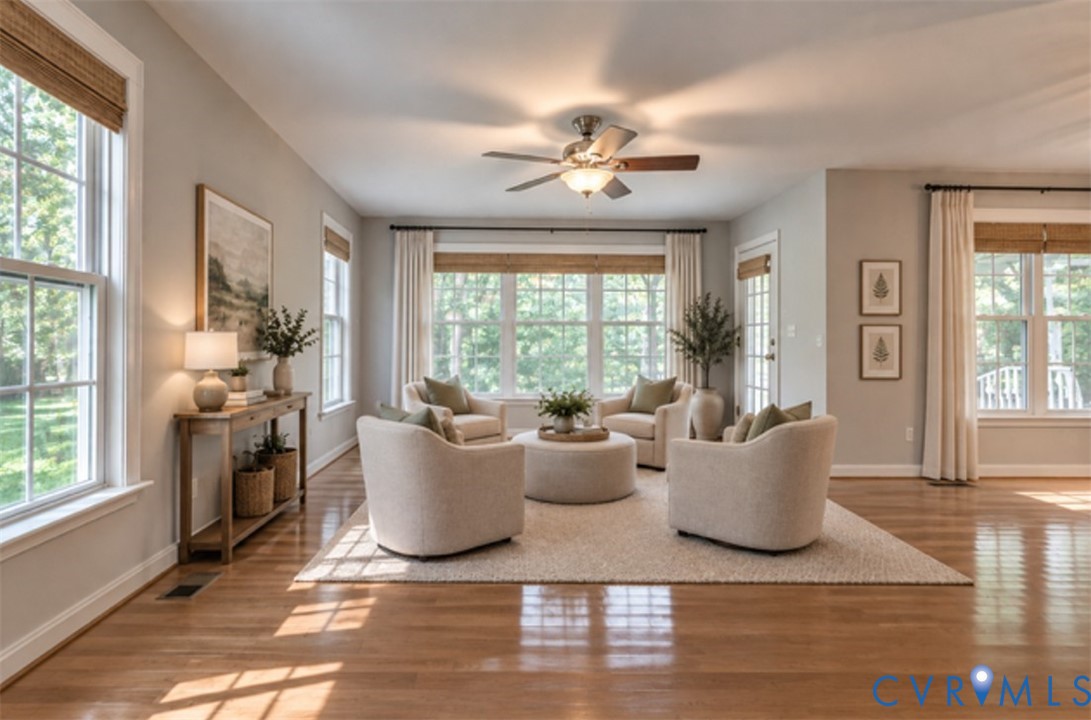 Hardwood flooring throughout, abundant natural light from multiple windows, ceiling fan with integrated lighting, recessed lighting, and a white paneled door