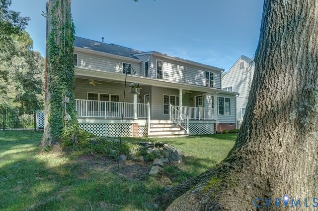 Rear exterior with a covered porch, white railing, and a fenced perimeter