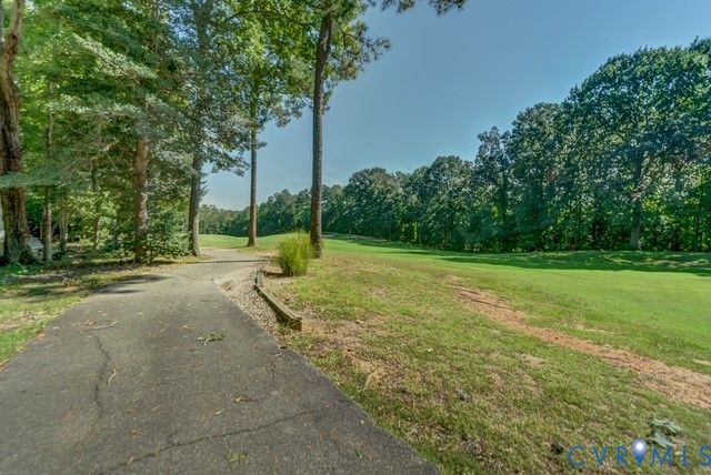 Expansive green space bordered by mature trees and a paved path