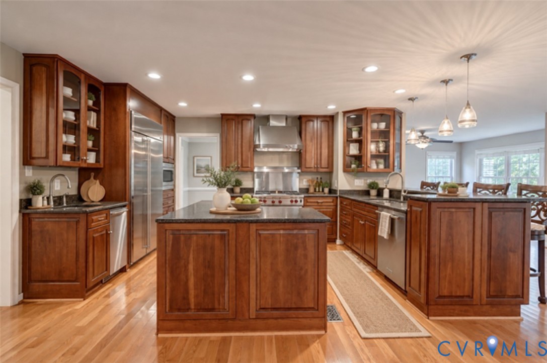 Kitchen featuring wood-finish flooring, dark countertops, full-height cabinetry, stainless steel appliances, and recessed lighting