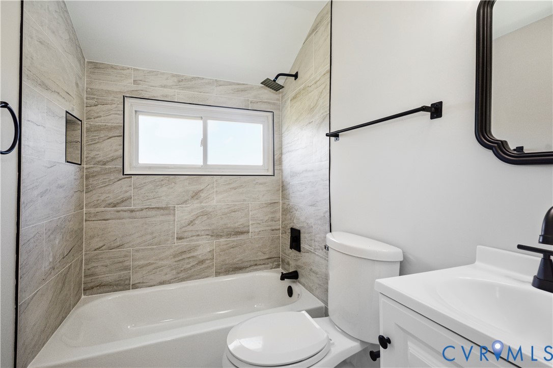 Tub-shower combination with tiled surround, built-in shower niche, and matte black fixtures