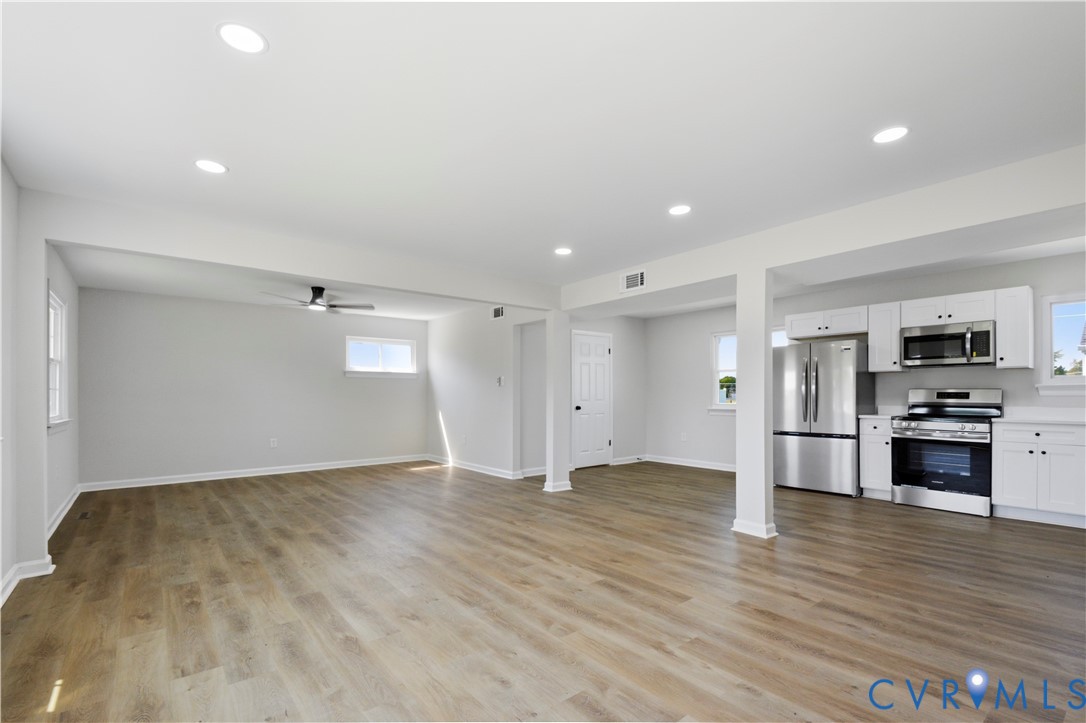 Open-concept living space with wood-finish flooring, recessed lighting, and a ceiling fan