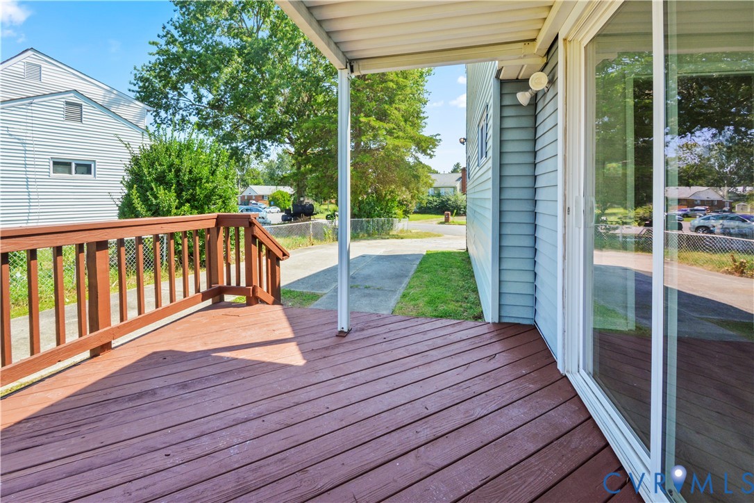 Covered wood-finish deck with railing, siding exterior, and a glass sliding door
