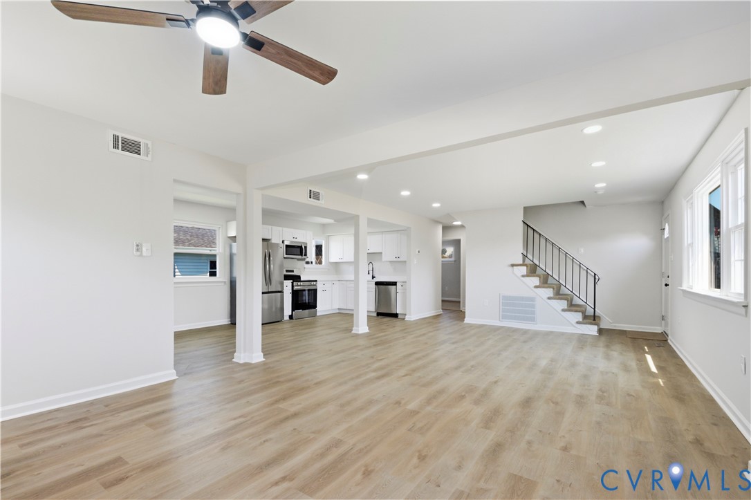 Wood-finish flooring throughout, recessed lighting, white cabinetry, stainless steel appliances, and a ceiling fan with integrated lighting