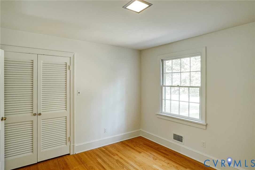 Bedroom #2 with hardwood flooring, louvered bi-fold closet doors and overhead lighting.