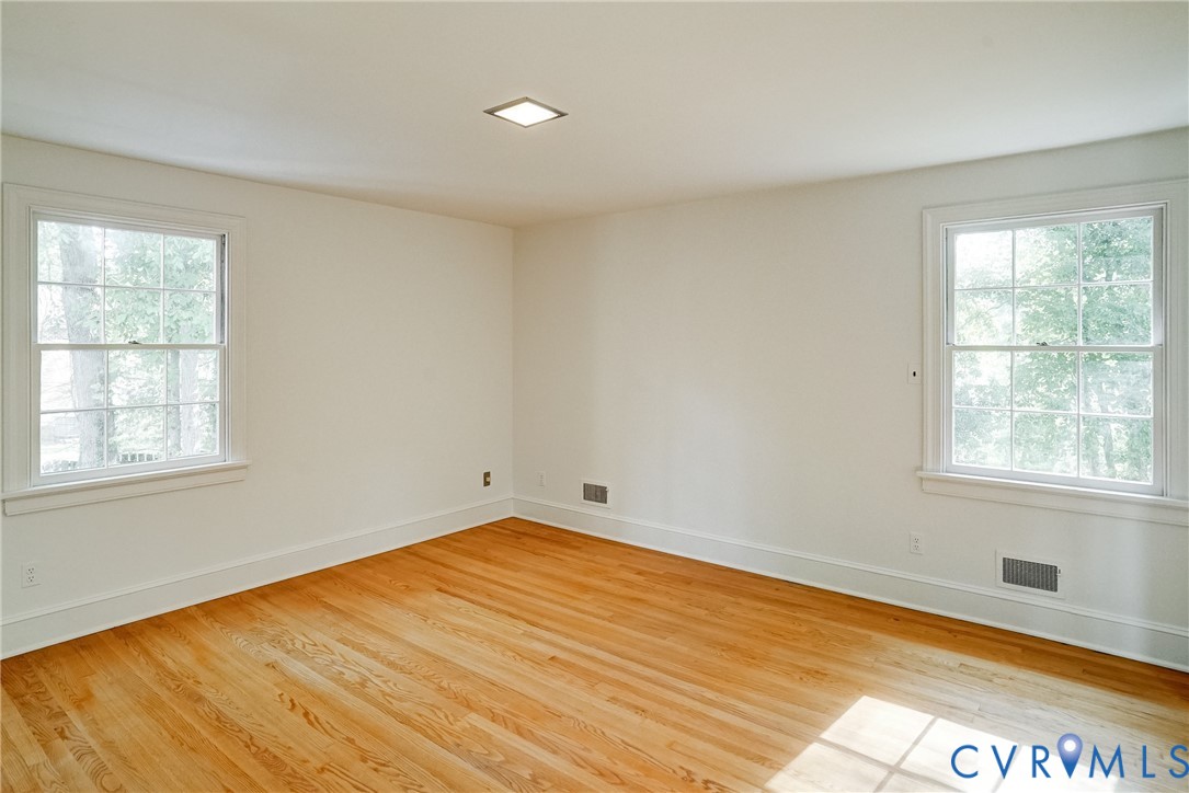 Primary bedroom with hardwood flooring, closet, overhead lighting and en suite bath