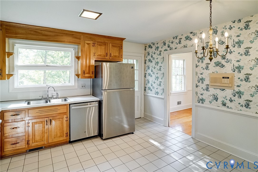 Eat in kitchen featuring wood cabinetry, stainless steel appliances, a double basin sink, and tile flooring