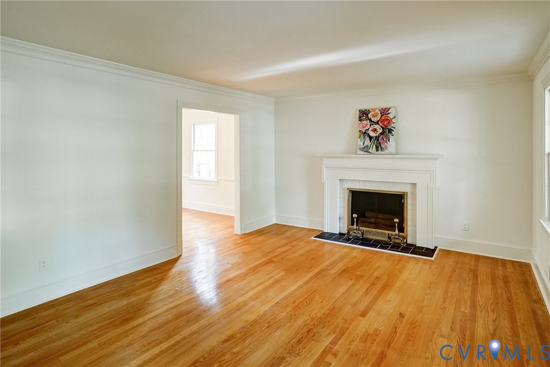 Spaciouse living room with hardwood flooring, crown molding and fireplace with mantle.  Opens to dining room