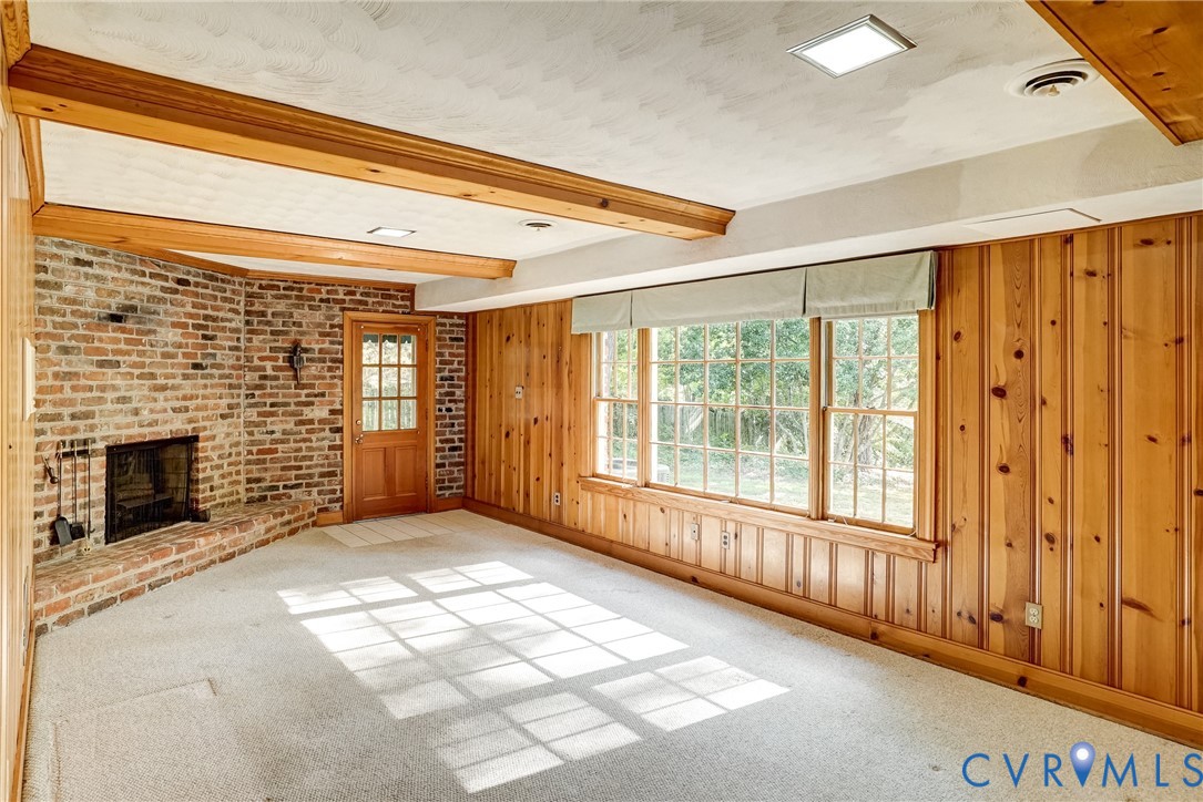 Lower level family room with exposed brick fireplace with a raised hearth, wood paneling and exposed wood ceiling beams.  Plus fantastic view of the backyard!