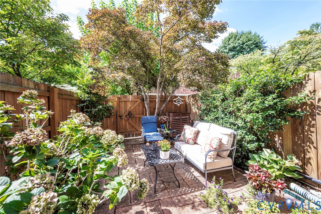 Private outdoor patio with a stone paver surface, wood privacy fencing, and mature landscaping