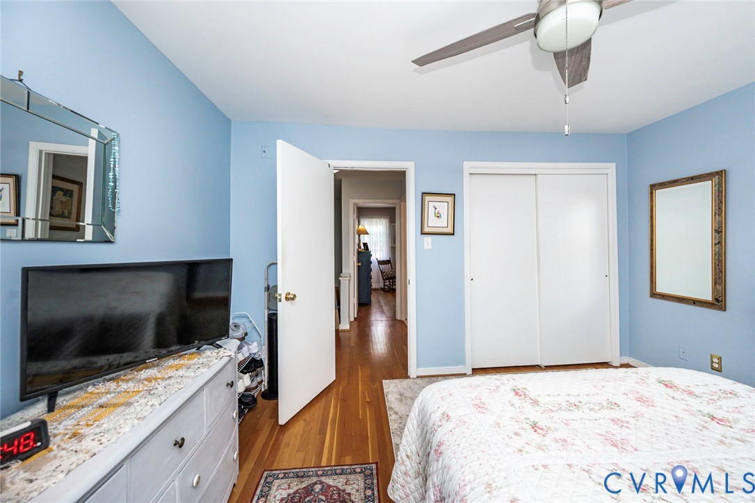 Hardwood flooring, light blue wall paint, and a ceiling fan with light fixture