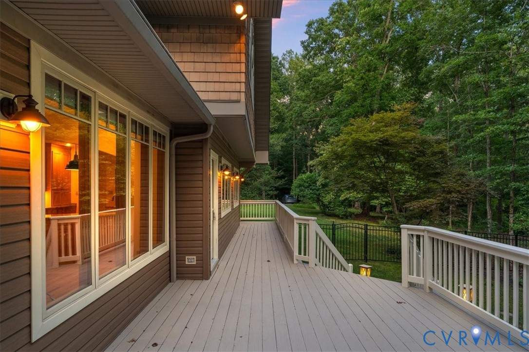 Expansive outdoor deck with composite decking, white railing, exterior wall lighting, and expensive wrap around outer deck.