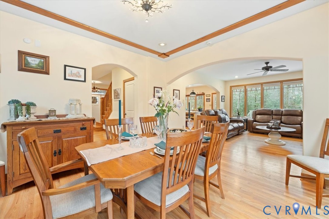 Archways connecting spaces, chandelier lighting, hardwood flooring, wall-mounted artwork, and a built-in wooden sideboard