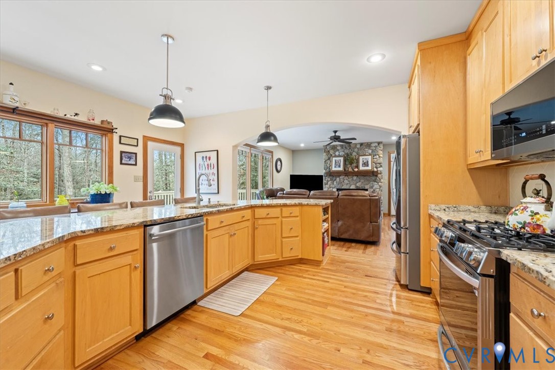 Kitchen with hardwood-finish flooring, light wood cabinetry, granite-finish countertops, and stainless steel appliances