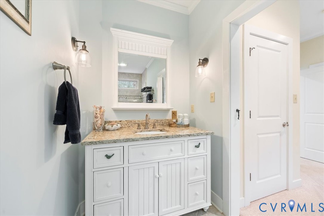 Vanity with a granite countertop, under-mount sink, and dual sconce lighting. Walk-in shower.