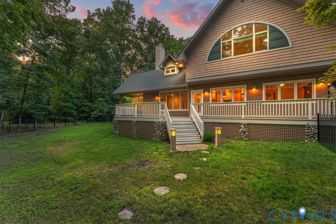 Expansive outdoor deck with composite decking, white railing, exterior wall lighting, and expensive wrap around outer deck.