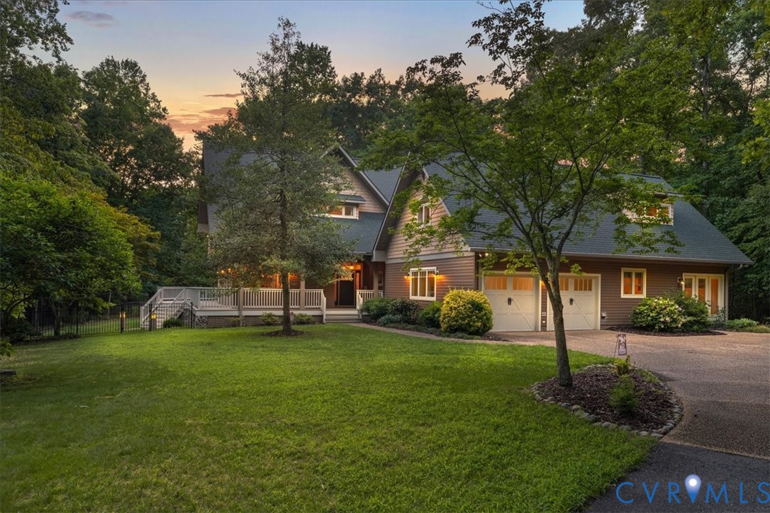 Craftsman-style, custom-built home with a wrap-around porch. Features include exterior lighting, a paved driveway, and established landscaping.