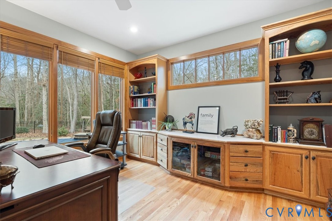 Expansive windows with natural hardwood frames, custom built-in cabinetry, integrated bookshelves, wood-finish flooring, and a recessed ceiling light fixture