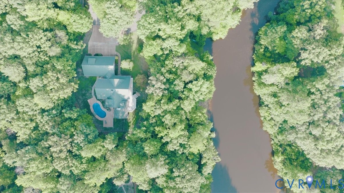Property with a private pool, surrounded by mature trees, and an adjacent natural waterway