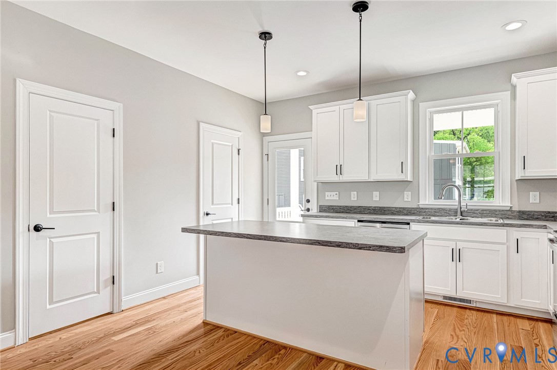 Kitchen with wood-finish flooring, white cabinetry, a center island with countertop seating, recessed lighting, and pendant lighting fixtures