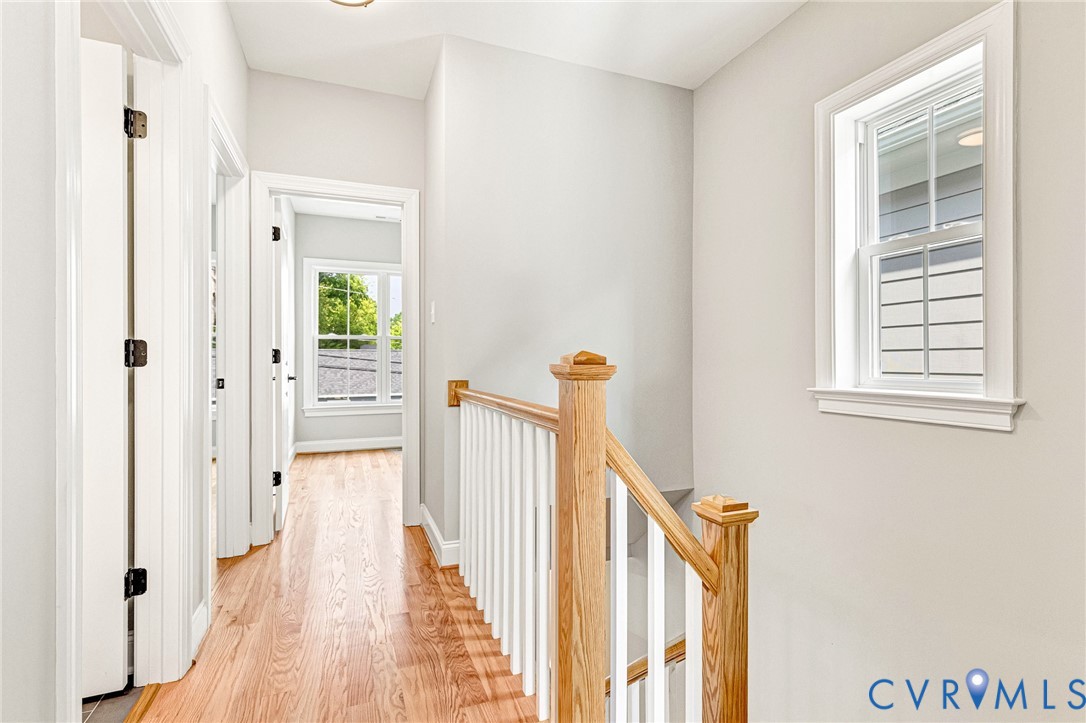 Hardwood flooring, painted interior walls, white trim, wood staircase newel post and handrail, and a double-hung window