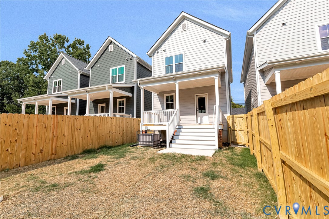 Private backyard with wood fencing, a covered porch, and exterior stairs