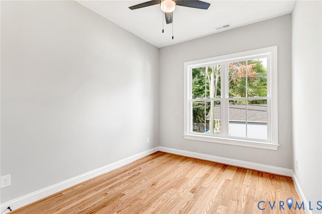 Hardwood flooring, white wall paint, white trim, ceiling fan, and a double-hung window