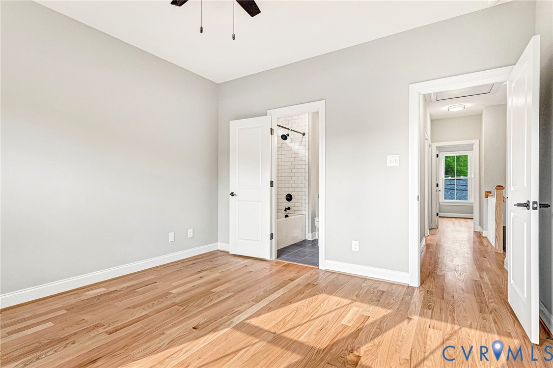 Hardwood flooring, light gray wall finish, white trim, ceiling fan, and white paneled doors