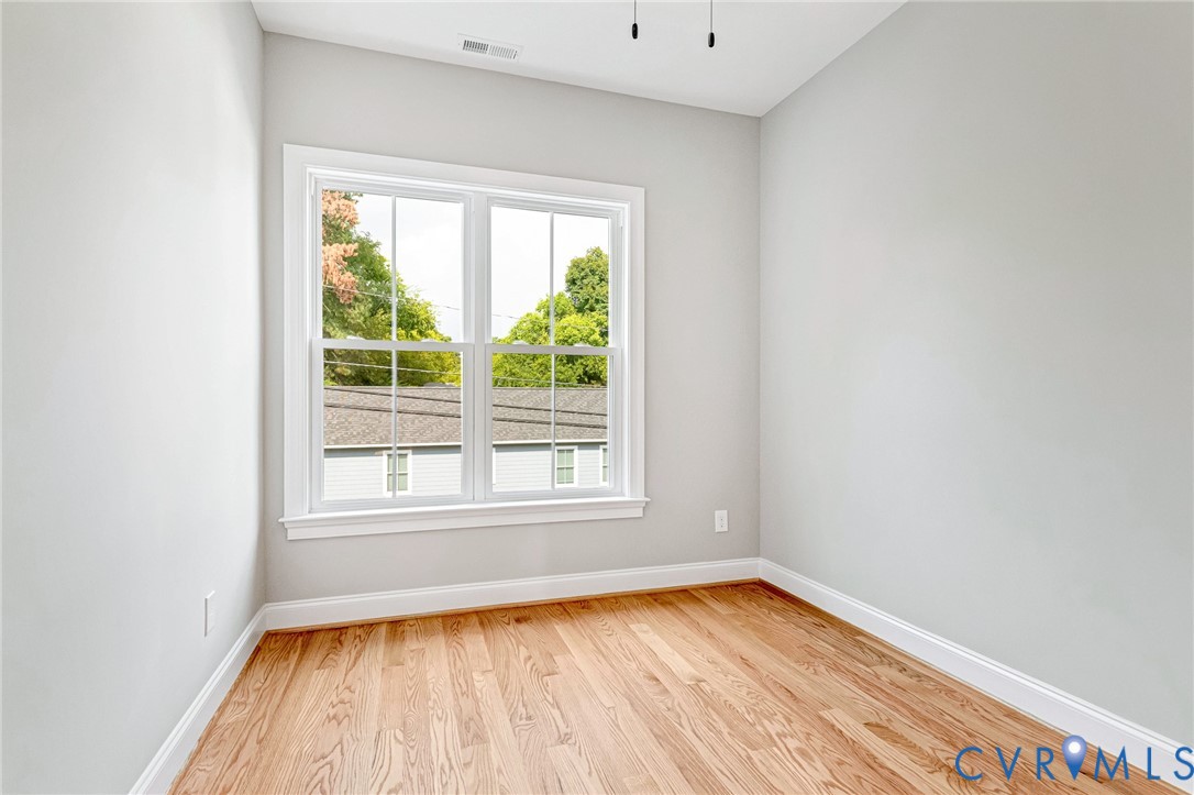Hardwood flooring, painted walls, white trim, and a double-hung window