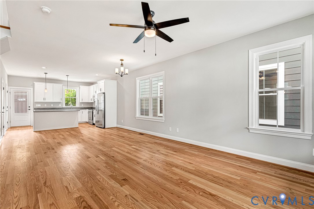 Spacious open-concept living area showcasing hardwood flooring, recessed ceiling lighting, and a ceiling fan with wood and black metal accents Spacious open-concept living area showcasing hardwood flooring, recessed ceiling lighting, and a ceiling fan with wood and black metal accents