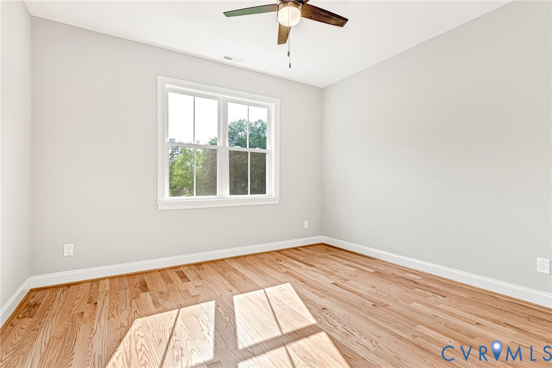 Wood-finish flooring, white trim, a double-hung window, and a ceiling fan