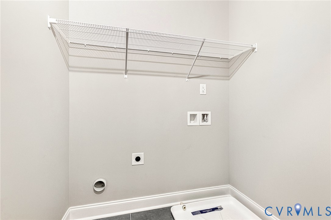 Laundry area featuring a white wire shelf, utility sink, and tile flooring