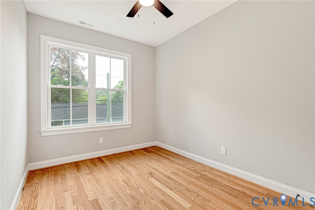 Hardwood flooring, painted walls, ceiling fan, and a double-hung window with white trim