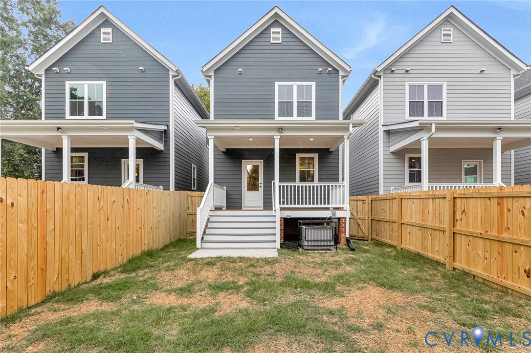 Rear exterior featuring a covered porch, white railings, and a fenced yard with a wood privacy fence