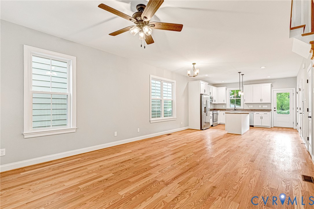 Hardwood flooring throughout, a ceiling fan with light fixture, and white window shutters
