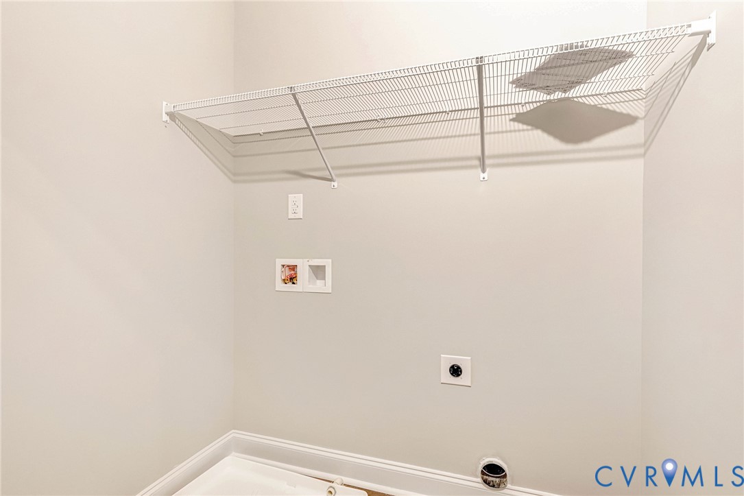 Laundry area featuring a white wire shelving unit, appliance hookups, and light gray wall paint