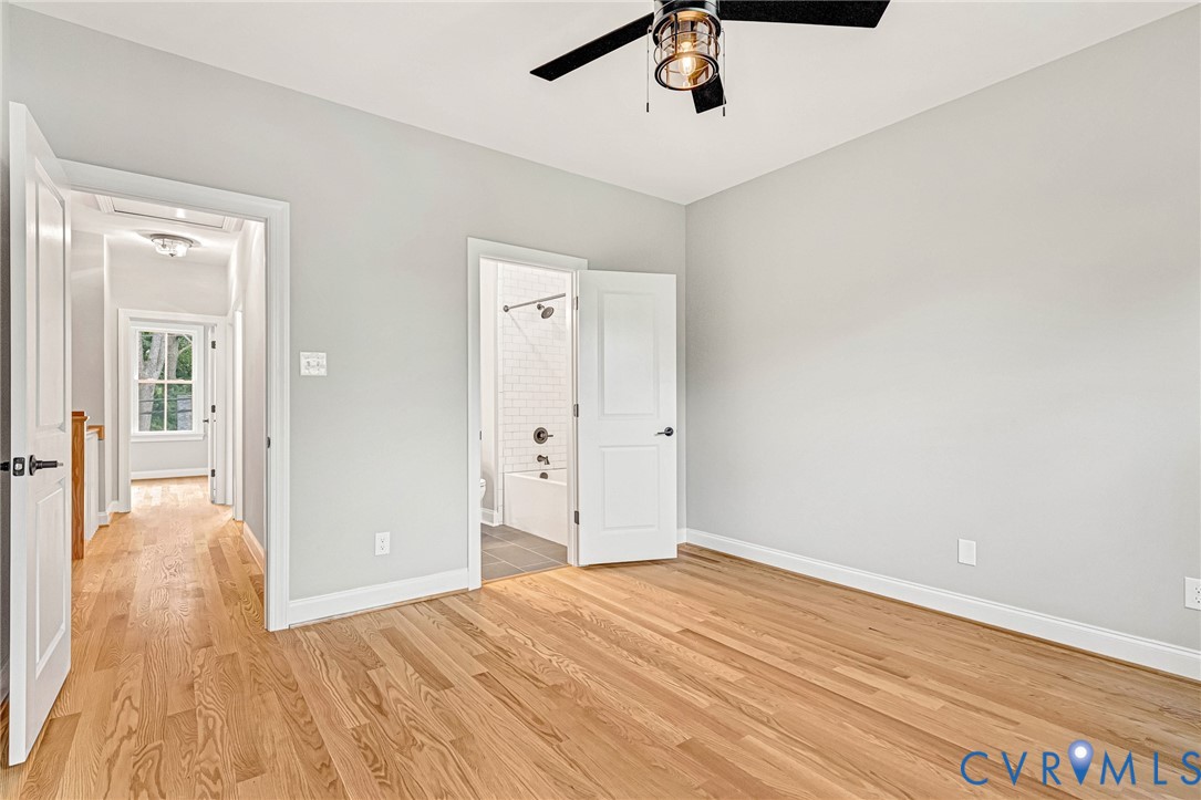 Hardwood flooring, light gray wall finishes, a modern ceiling fan, and a white paneled door