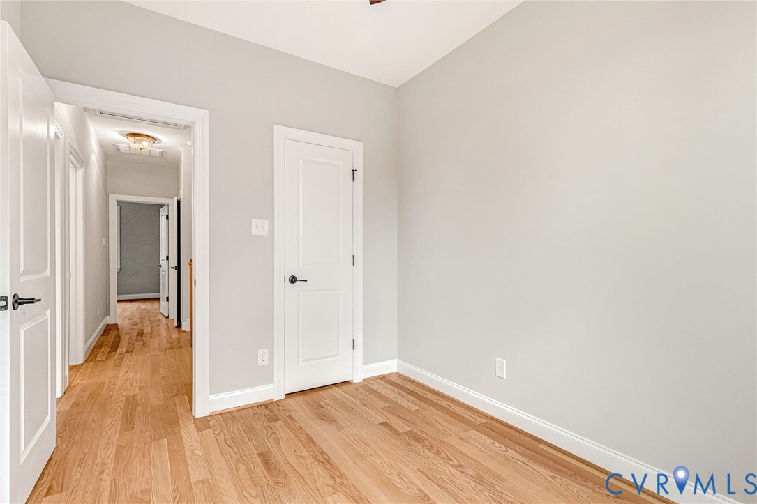 Hardwood flooring throughout, neutral wall tones, white trim, and white paneled doors with dark hardware
