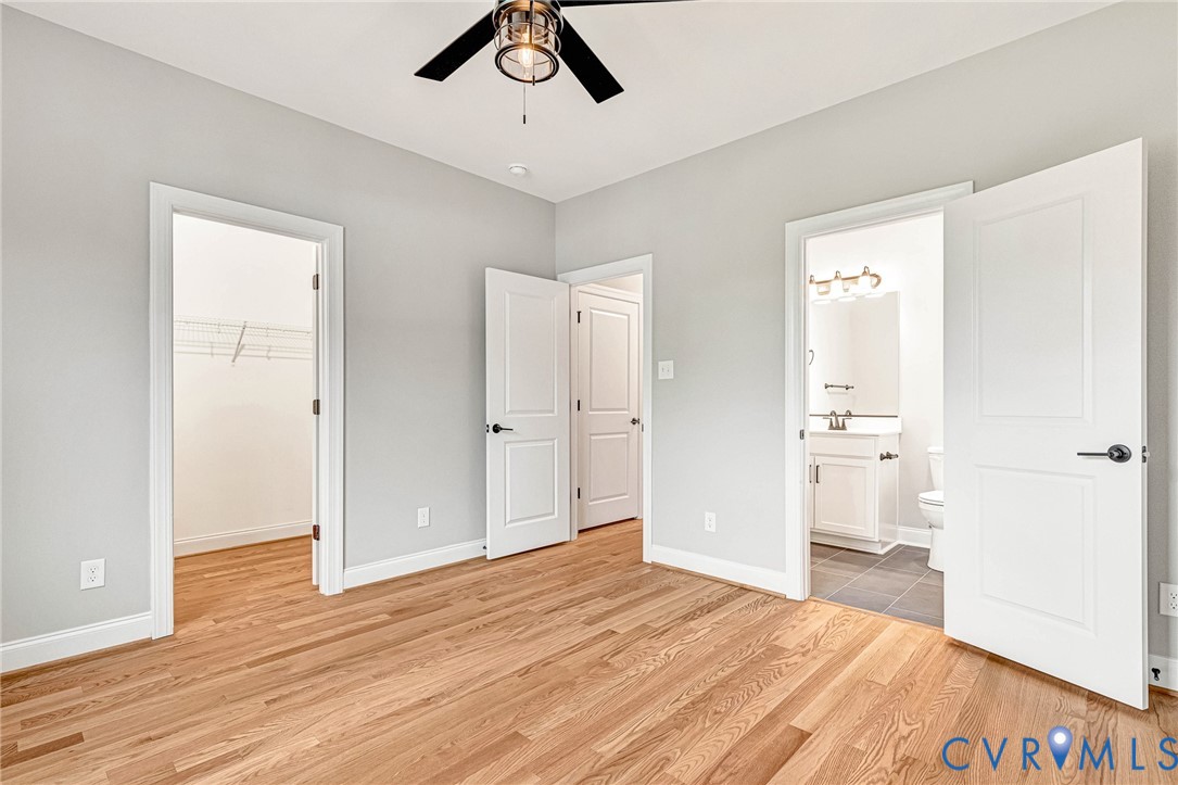 Hardwood flooring, light gray walls, ceiling fan, and white doors with dark hardware