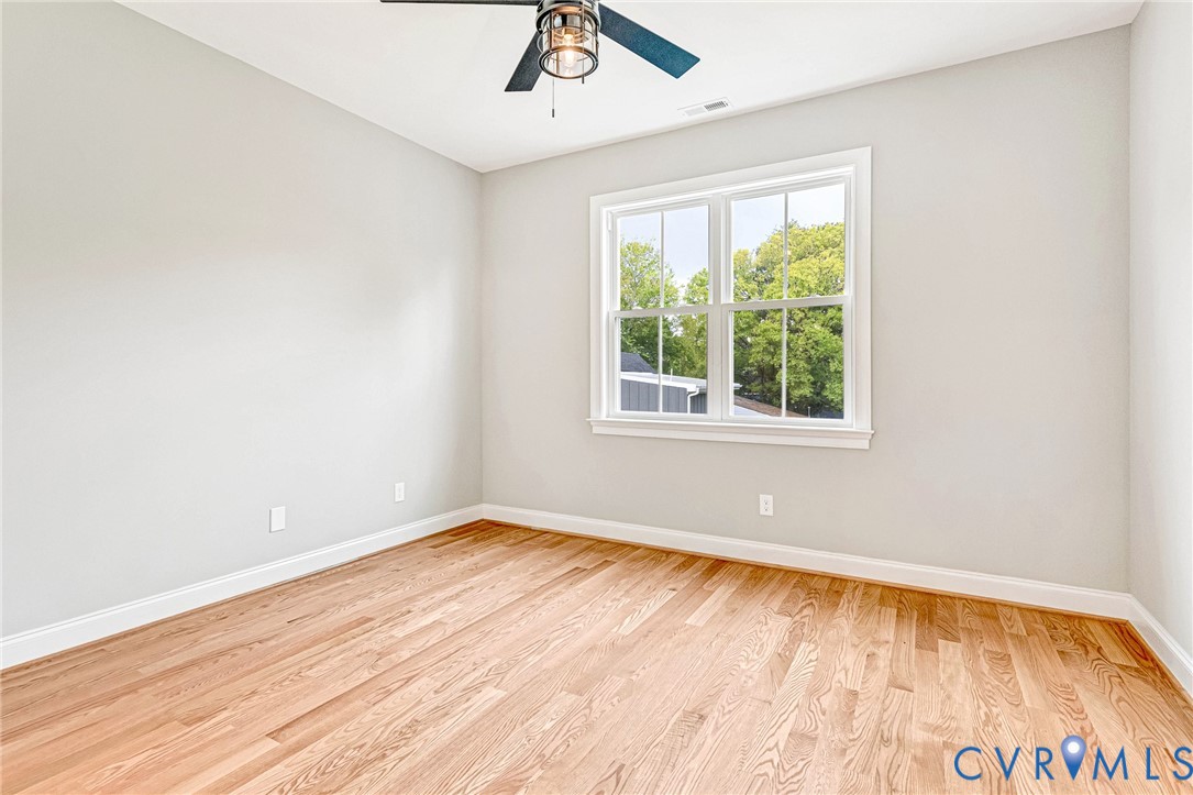 Hardwood flooring, painted walls, white trim, double-hung window, and a ceiling fan