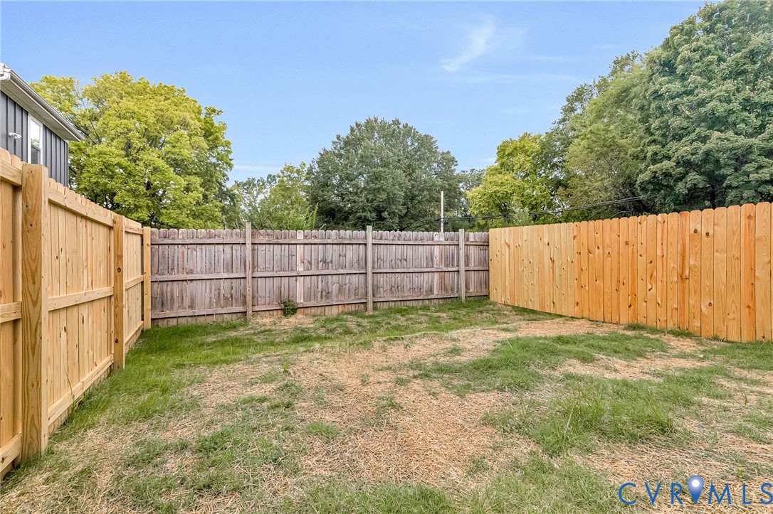 Expansive outdoor space featuring a new wood fence and established perimeter fencing