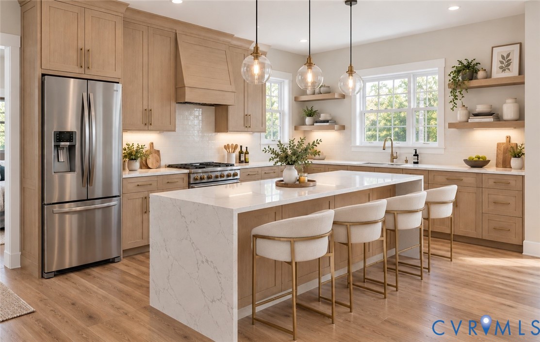 Well-appointed kitchen featuring light wood-finish cabinetry, stainless steel appliances, a large center island with a waterfall countertop, and pendant lighting