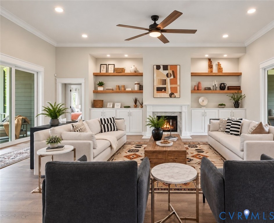 Spacious living area featuring wood-finish flooring, a ceiling fan, recessed lighting, and a fireplace with a white mantel