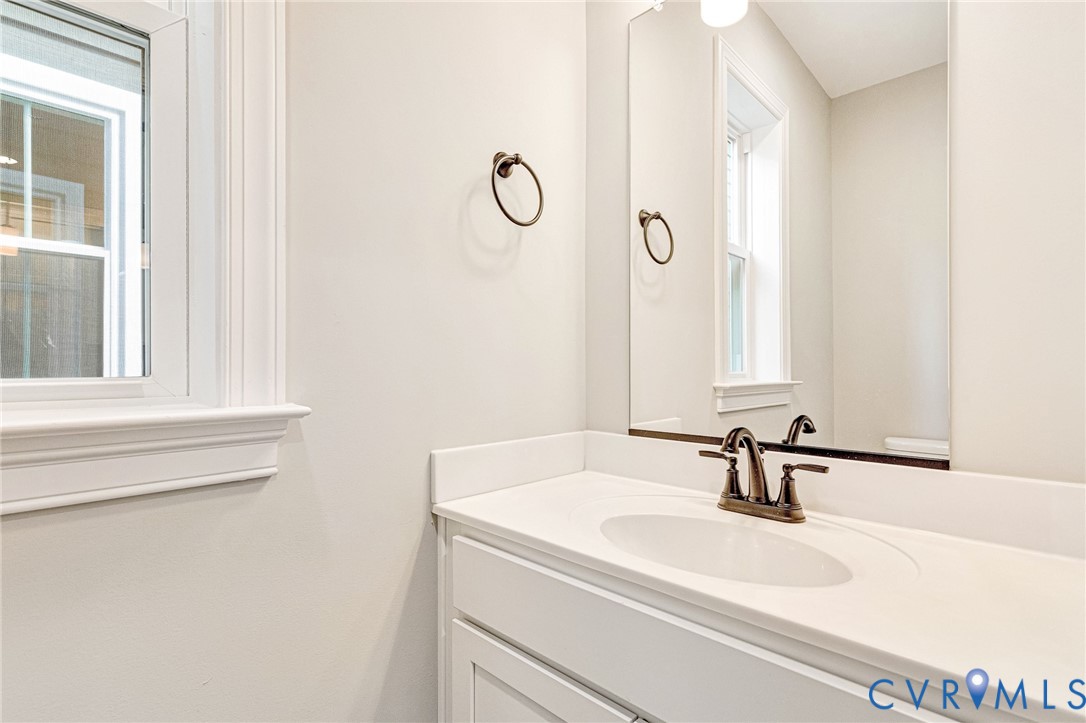 White vanity with integrated sink, bronze-finish faucet, and a large wall mirror